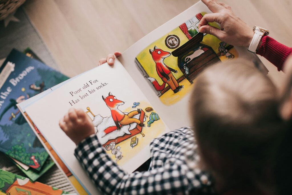 pexels-photo-1741230-1741230 A child and adult reading an illustrated storybook together in a cozy setting.