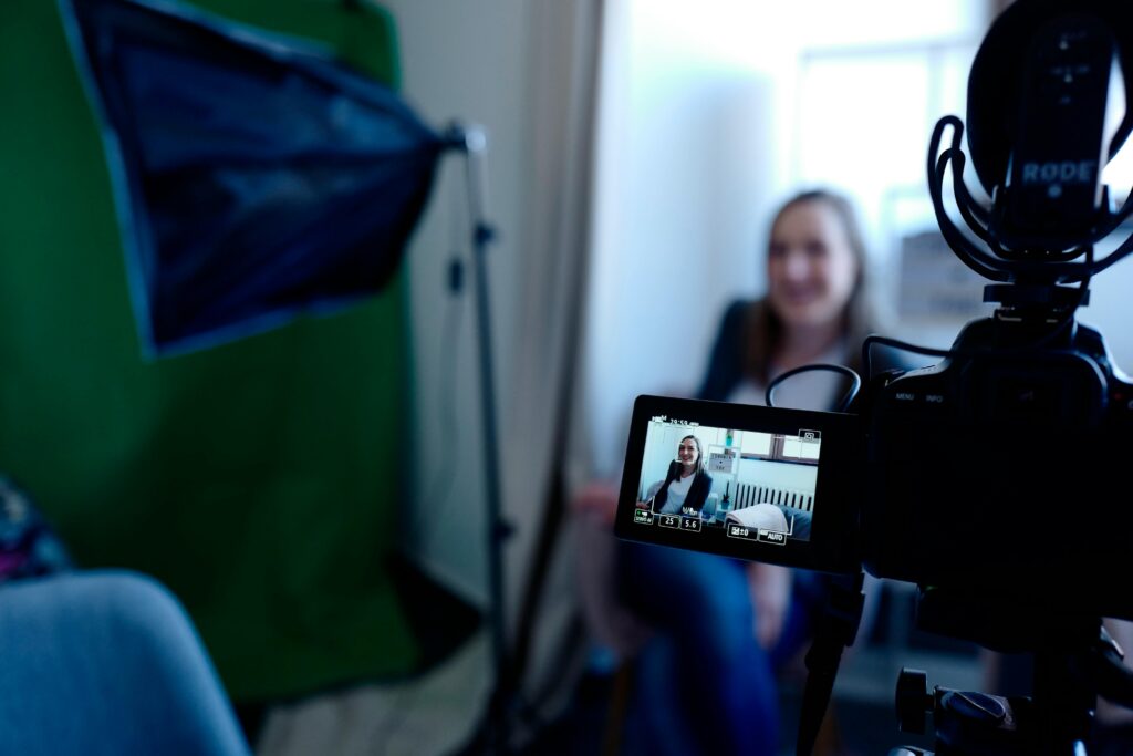 pexels-photo-2041396-2041396 Woman being recorded in a professional studio setup, using video camera and lighting equipment.