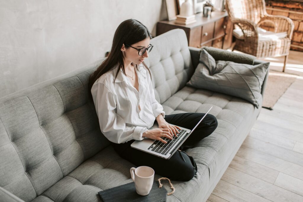 pexels-photo-4050291-4050291 Woman in a cozy home setting working on a laptop for remote work and relaxation.