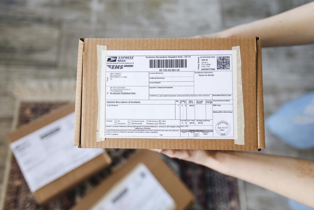 pexels-photo-4440788-4440788 Top view of hands holding an express mail parcel with a customs declaration.